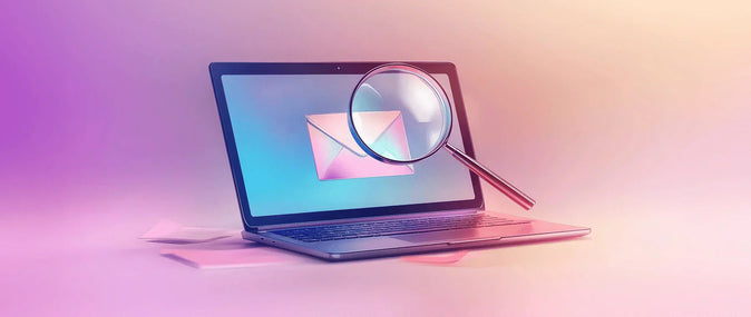 Otwarty laptop z ikoną koperty na ekranie oraz unoszącą się nad nią lupą.