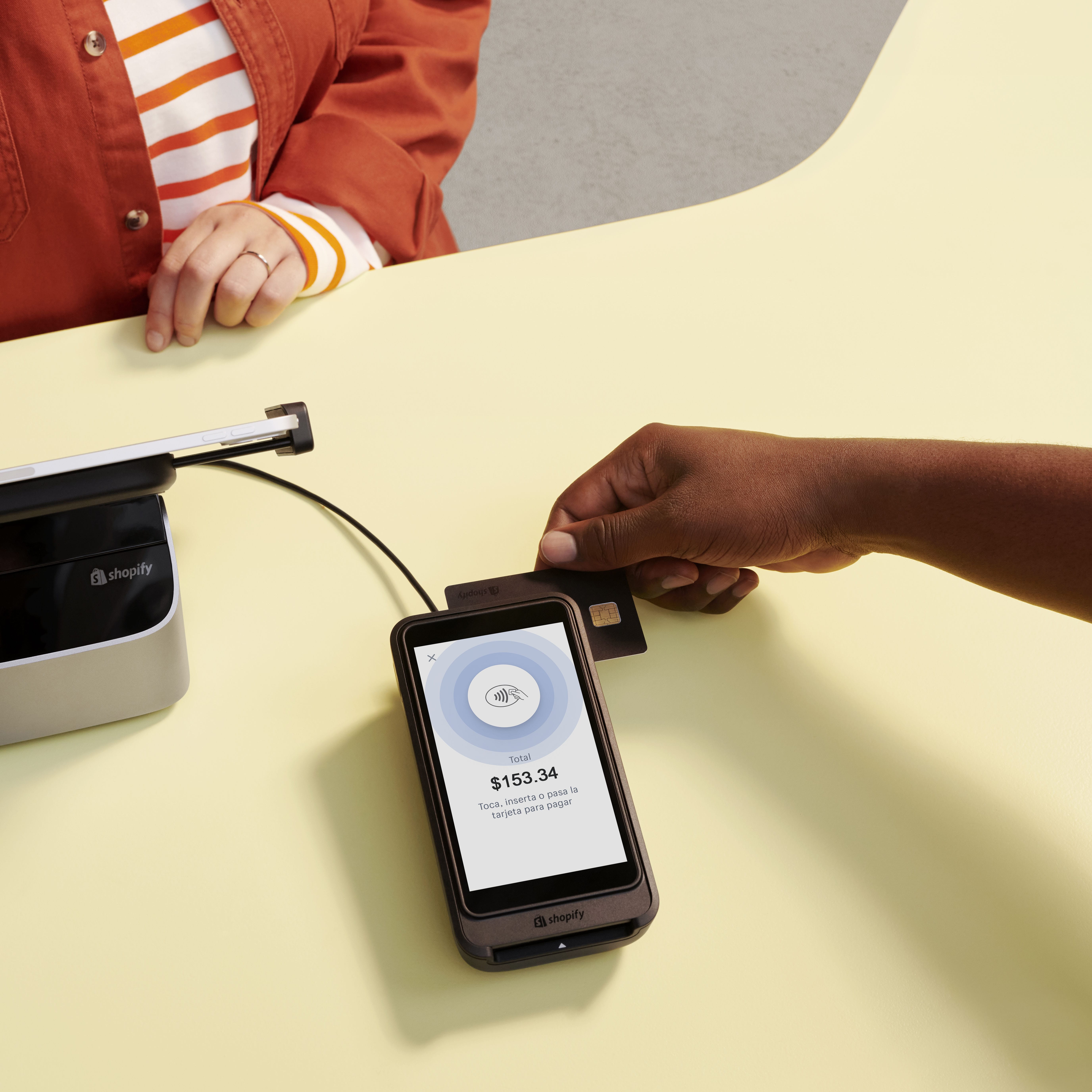Un cliente pasa su tarjeta por Shopify POS Terminal, que muestra el total de pago y opciones para colocar, insertar o pasar la tarjeta en la pantalla.