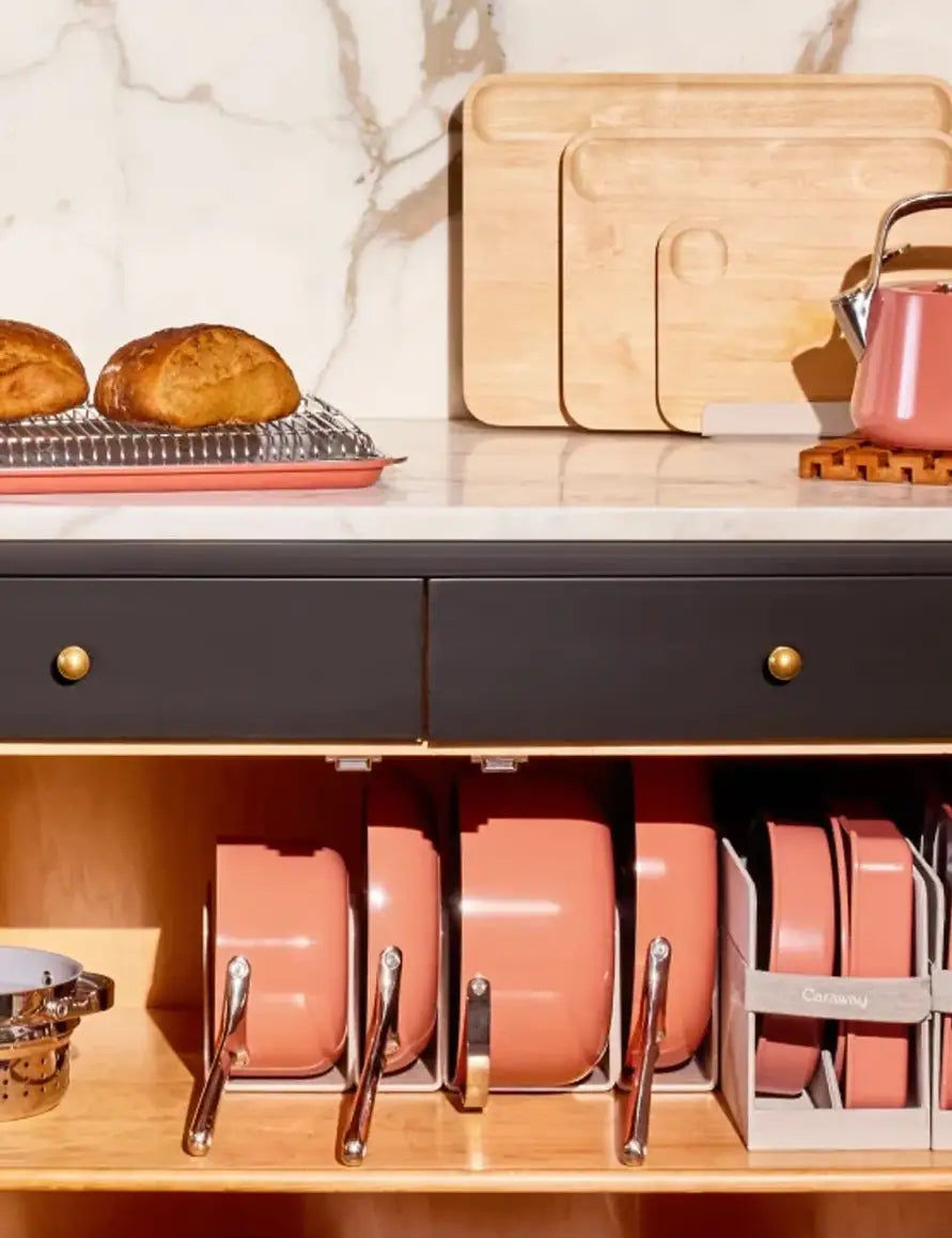 An array of salmon-colored cookware stacked in a kitchen cabinet.