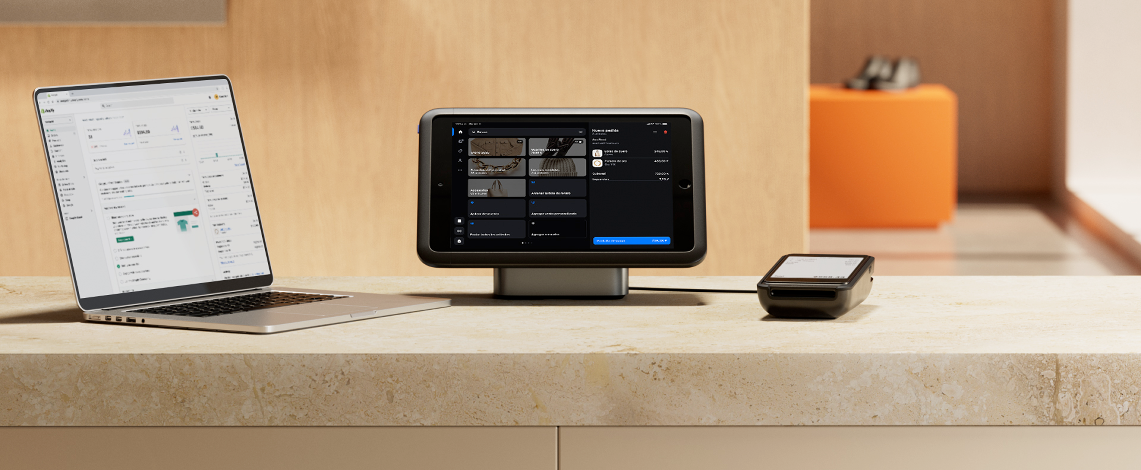 El mostrador de una tienda minorista con un conjunto completo de dispositivos. Una computadora portátil con la oficina administrativa de Shopify, una tablet con la aplicación Shopify POS y un terminal de POS con una pantalla de pago.