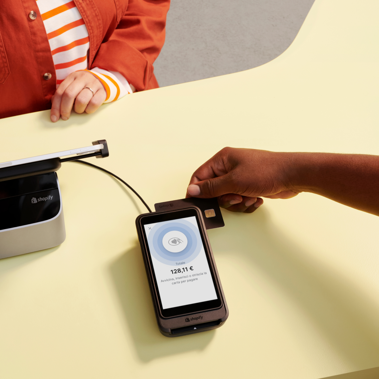 Una persona striscia la sua carta sullo Shopify POS Terminal, sul cui schermo è visualizzato il totale del pagamento e le opzioni per appoggiare, inserire o strisciare la carta.