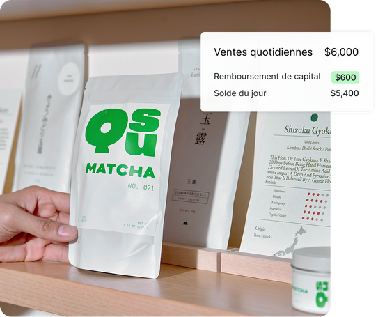Une main se tend vers un sachet de matcha sur une étagère en bois remplie de paquets de matcha et de thé