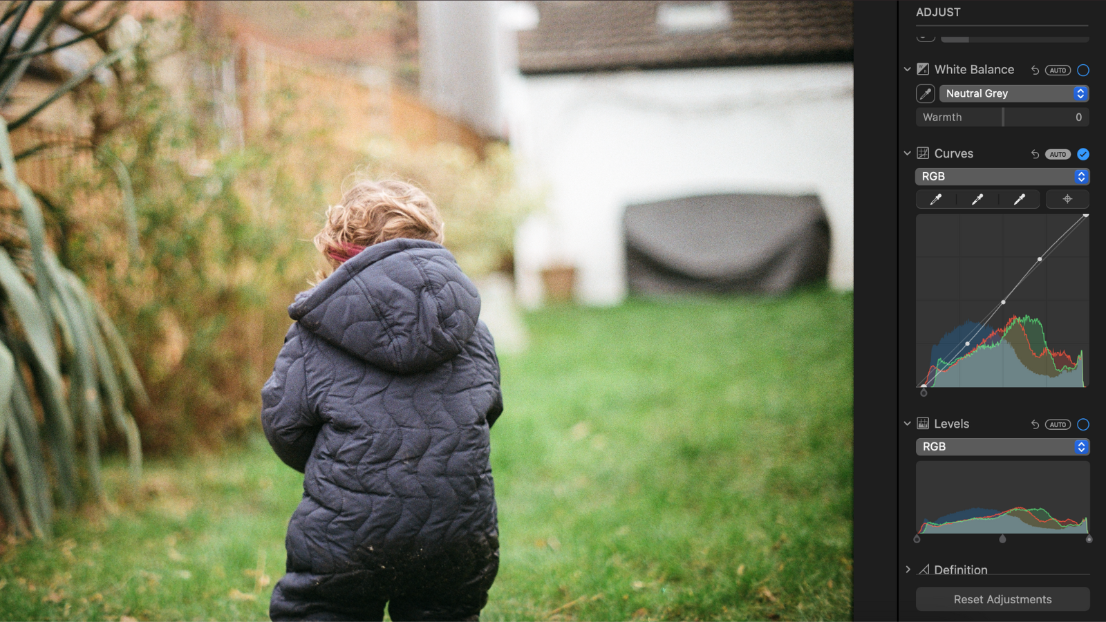 A child on a grass field with an Apple Photos UI sidebar.