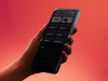 A hand holding a black Verifone Victa Mobile card reader against a red background
